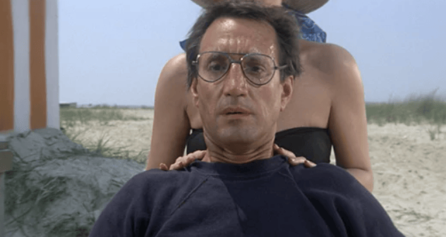 Film still of Chief Brody sitting tensely on a crowded beach in Jaws