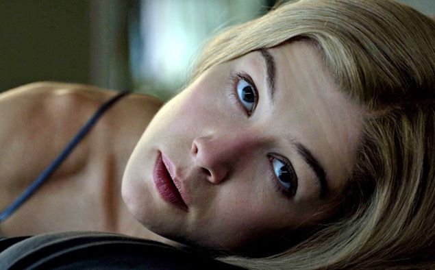 Rosamund Pike as Amy Dunne in Gone Girl, lying on her side staring directly at the camera