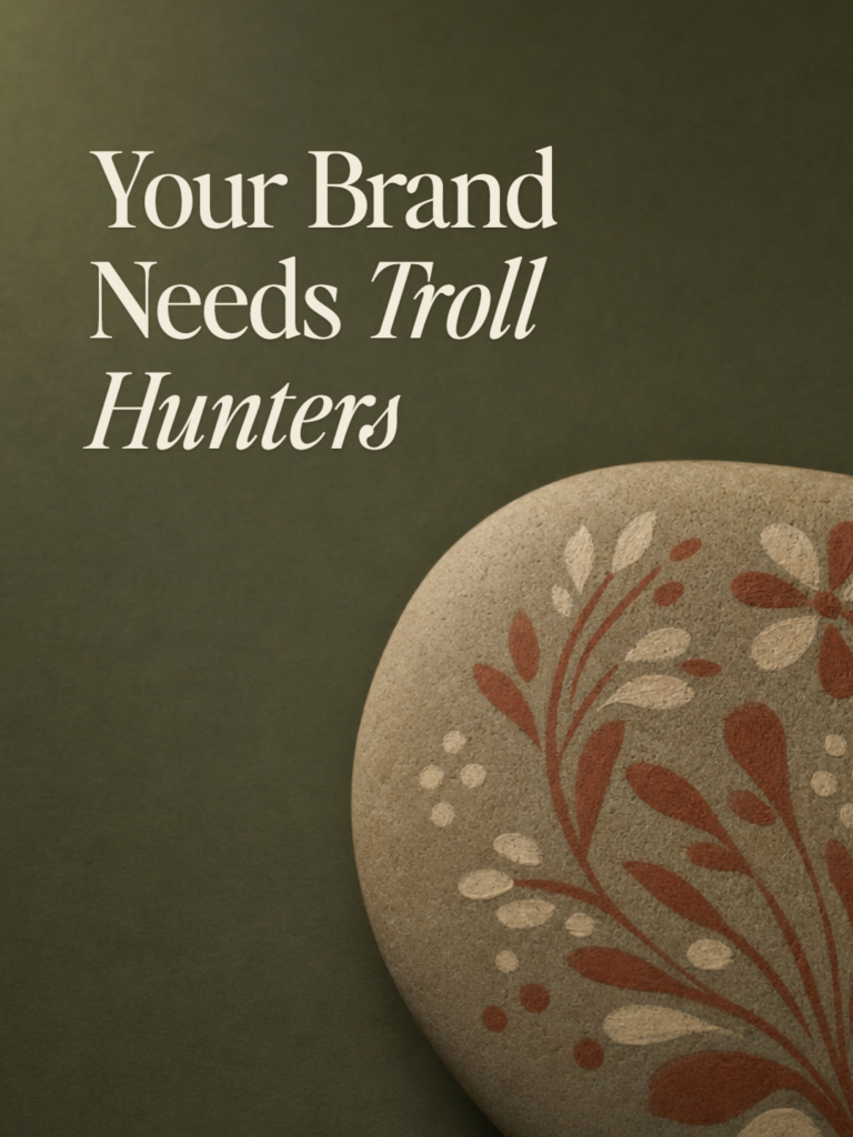 A smooth river stone hand-painted with a folk floral motif on deep olive — cover for Your Brand Needs Troll Hunters.